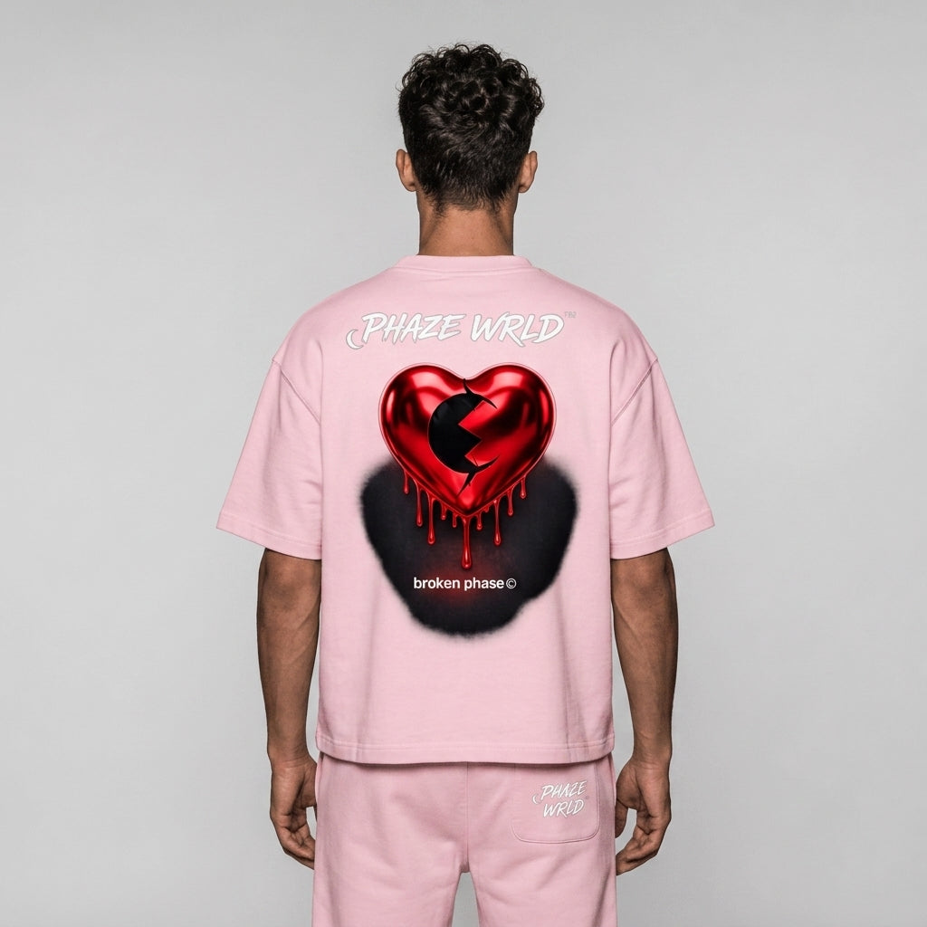 Back view of a premium baby pink oversized streetwear t-shirt featuring a metallic red dripping heart graphic and white Phaze Wrld branding.