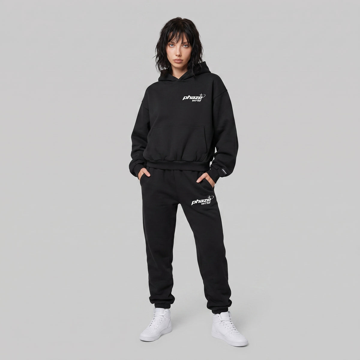 Front view of a model wearing the black Beyond the Phaze 999 hoodie, showing the 'phaze wrld' chest graphic.