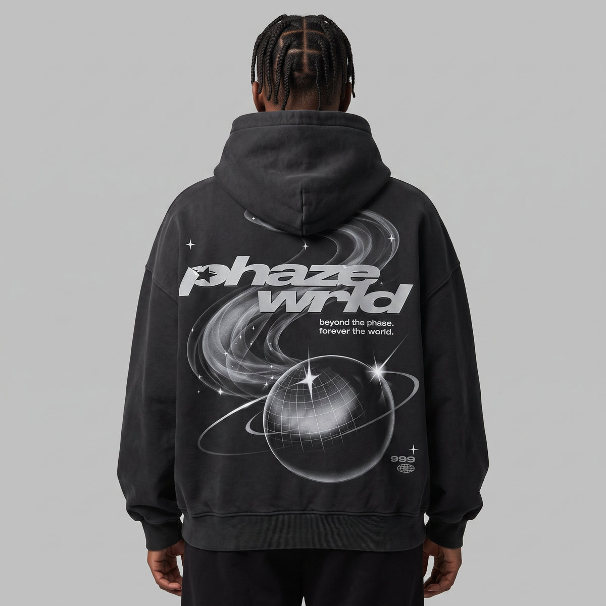 Rear view of a model in a faded black Beyond the Phaze 999 hoodie, highlighting the large back graphic with planet and stars.