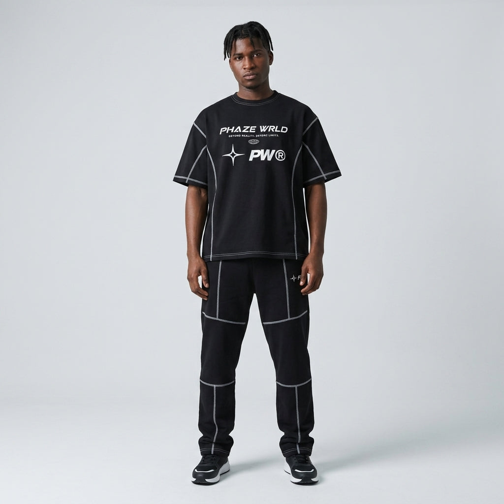 Black oversized streetwear t-shirt featuring white contrast stitching, paneled construction, and a futuristic white graphic print on the chest.