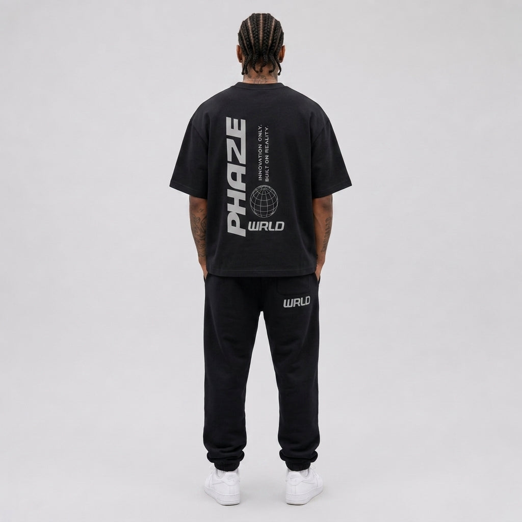 Back view of a premium black oversized heavyweight streetwear t-shirt with a vertical light grey PHAZE WRLD text and wireframe globe graphic.
