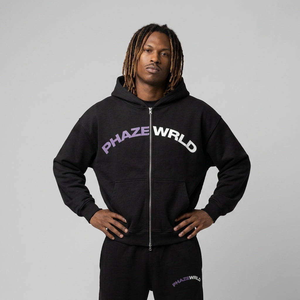A premium black oversized streetwear zip-up hoodie featuring a purple and white arched PHAZEWRLD graphic across the chest with drop shoulders.