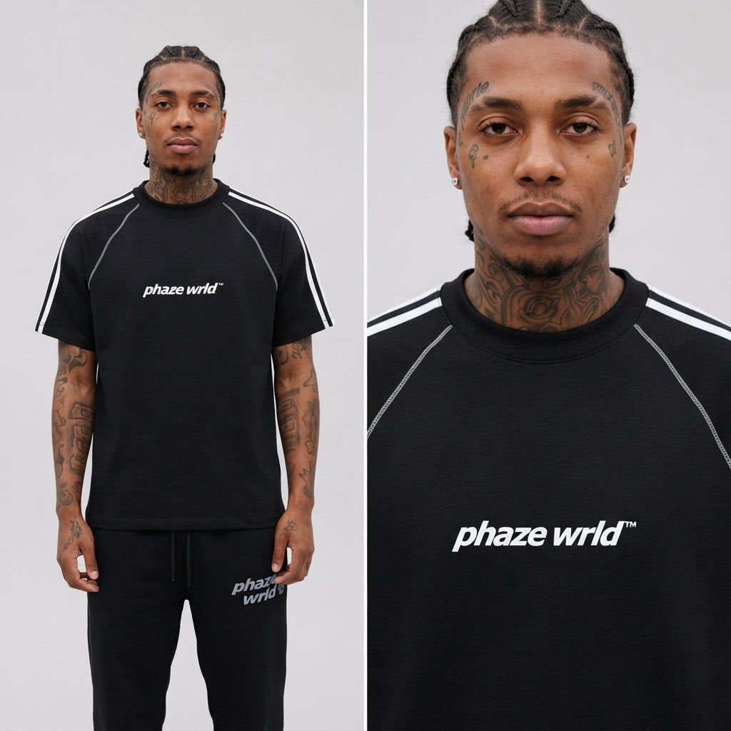 A flat lay lookbook photo of a premium black streetwear raglan t-shirt featuring contrast white stitching, shoulder stripes, and a white chest logo.