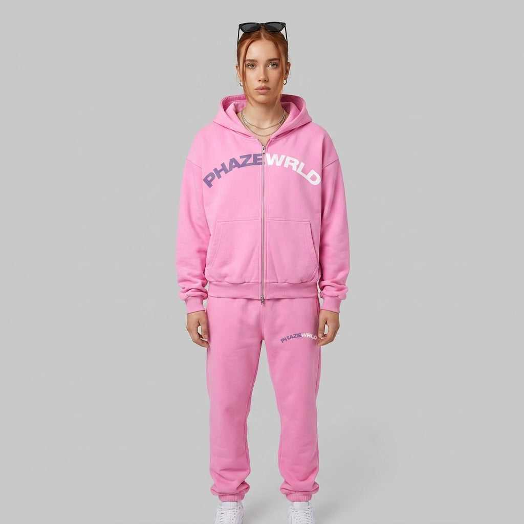A studio product photo of a premium bubblegum pink oversized zip-up streetwear hoodie featuring a two-tone purple and white arched chest graphic.