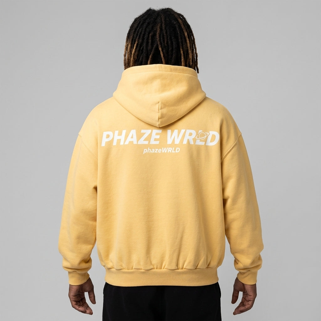 A premium butter yellow oversized streetwear hoodie featuring a bold white Phaze Wrld logo graphic on the back with a drop shoulder fit.