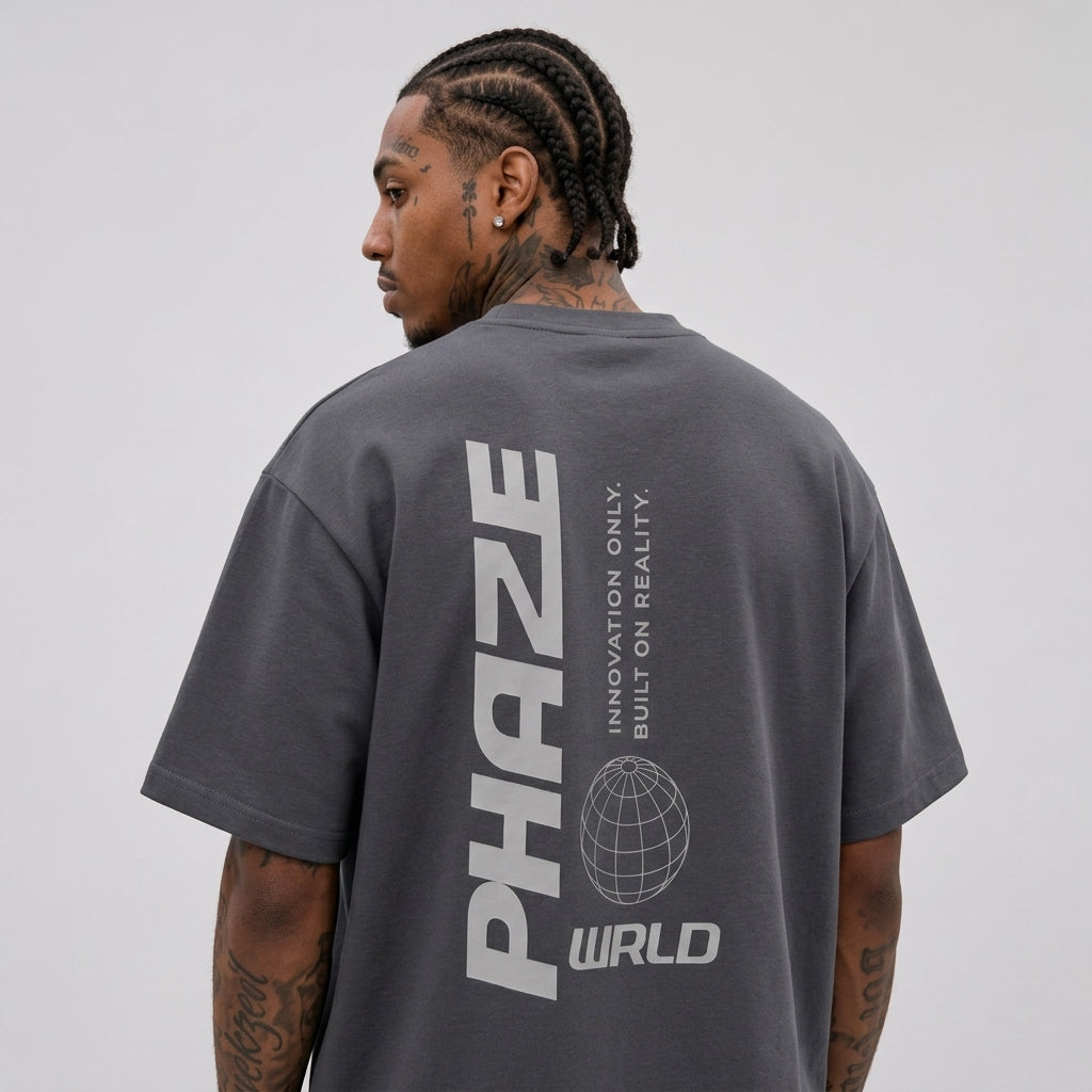 A flat-lay view of a premium charcoal grey oversized streetwear t-shirt featuring a light grey vertical graphic print with a wireframe globe on the back.