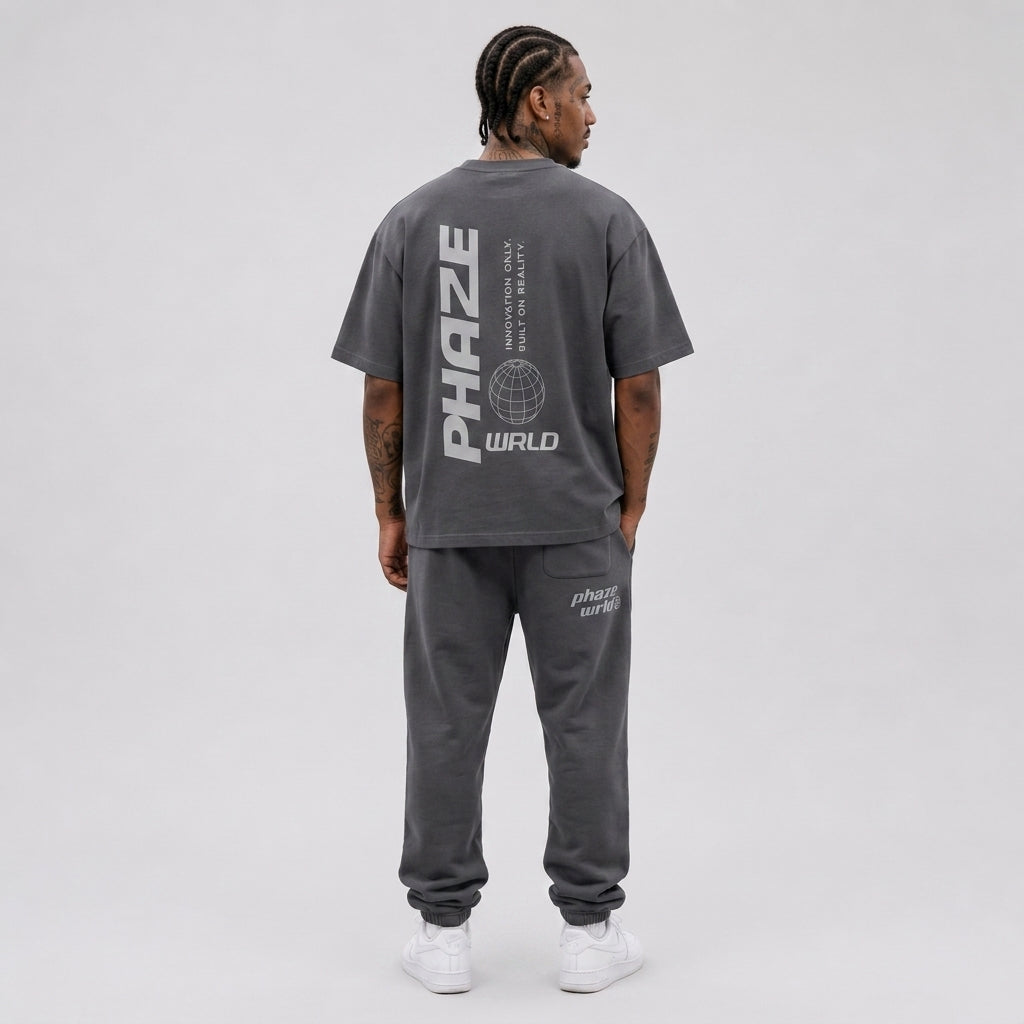 Back view of a premium oversized charcoal grey streetwear t-shirt featuring a vertical Phaze Wrld graphic and wireframe globe design.