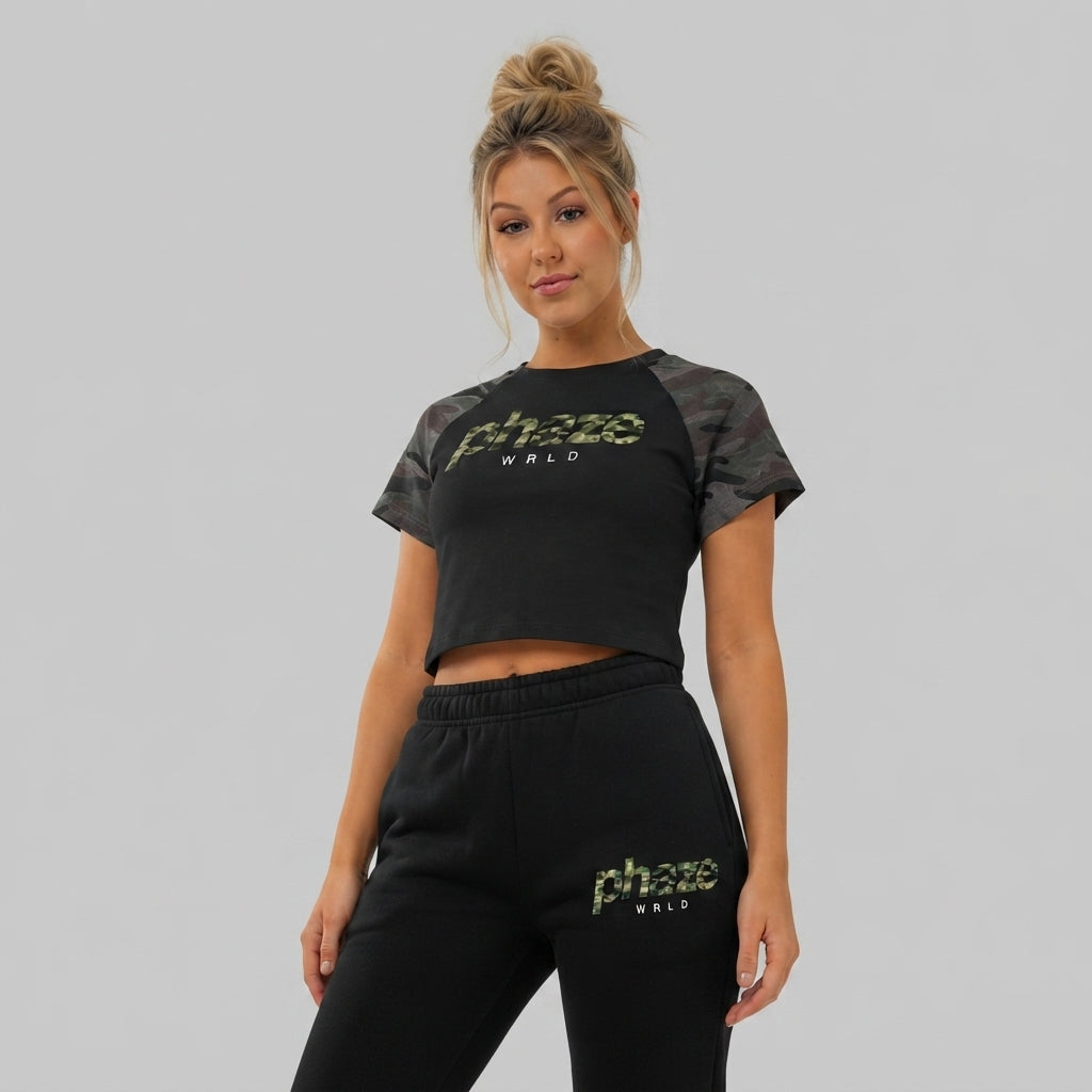 A cropped black raglan baby tee with green woodland camouflage short sleeves and a matching camo 'phaze WRLD' graphic printed on the chest.