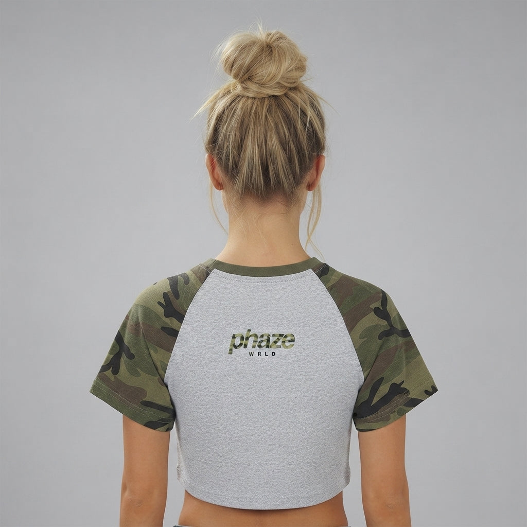 A cropped streetwear raglan baby tee featuring a heather grey cotton body, green woodland camouflage short sleeves, and a small center-chest logo.