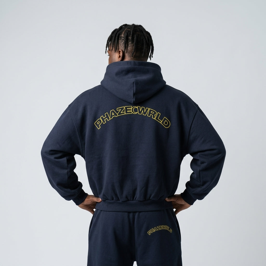 Back view of a premium dark navy oversized streetwear hoodie with a yellow arched "PHAZEWRLD" outline graphic on the back.