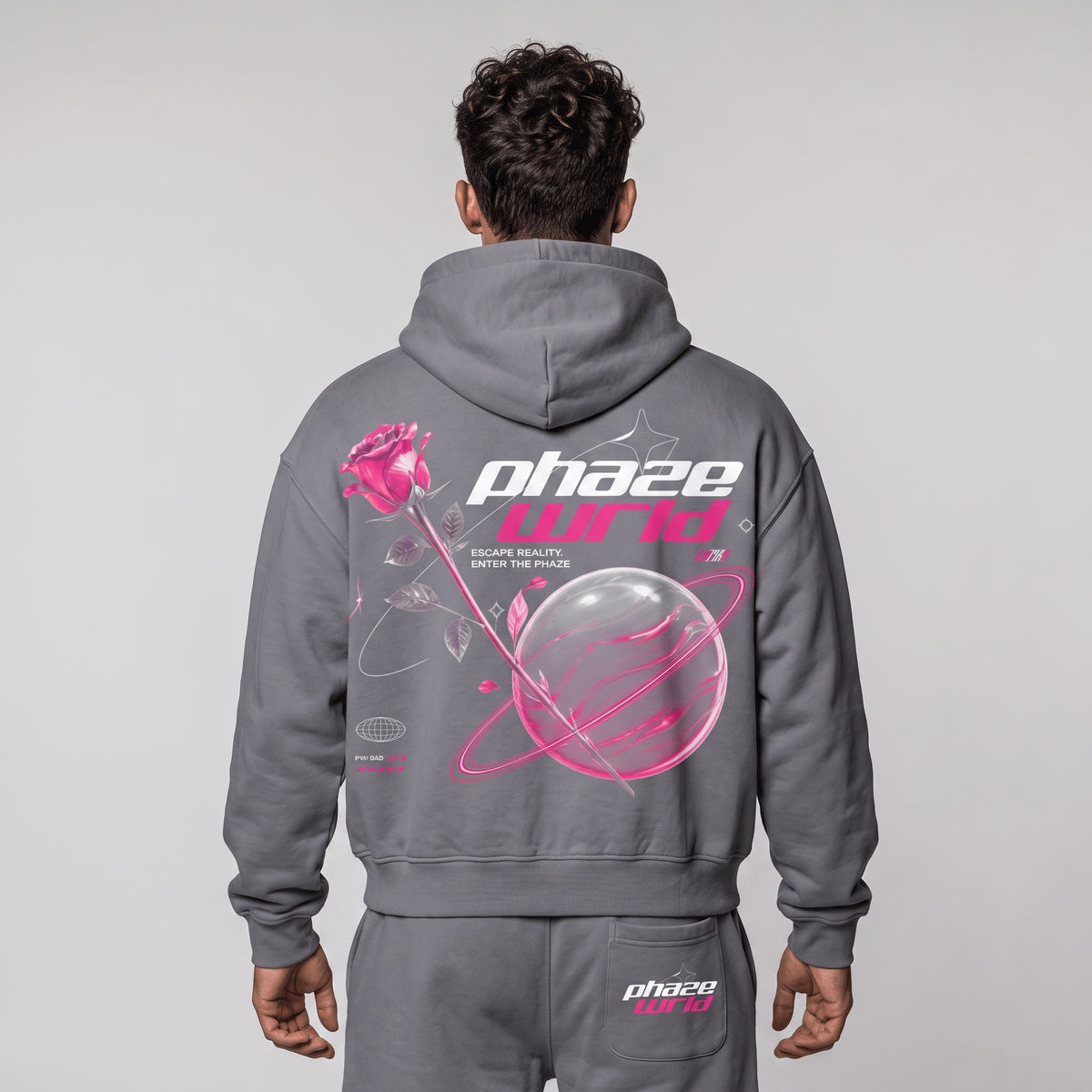 Model from behind wearing the Escape Reality grey boxy hoodie with a large pink and white back graphic.