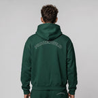 Back view of a premium forest green oversized streetwear hoodie featuring an arched white outline PHAZEWRLD graphic across the shoulders.