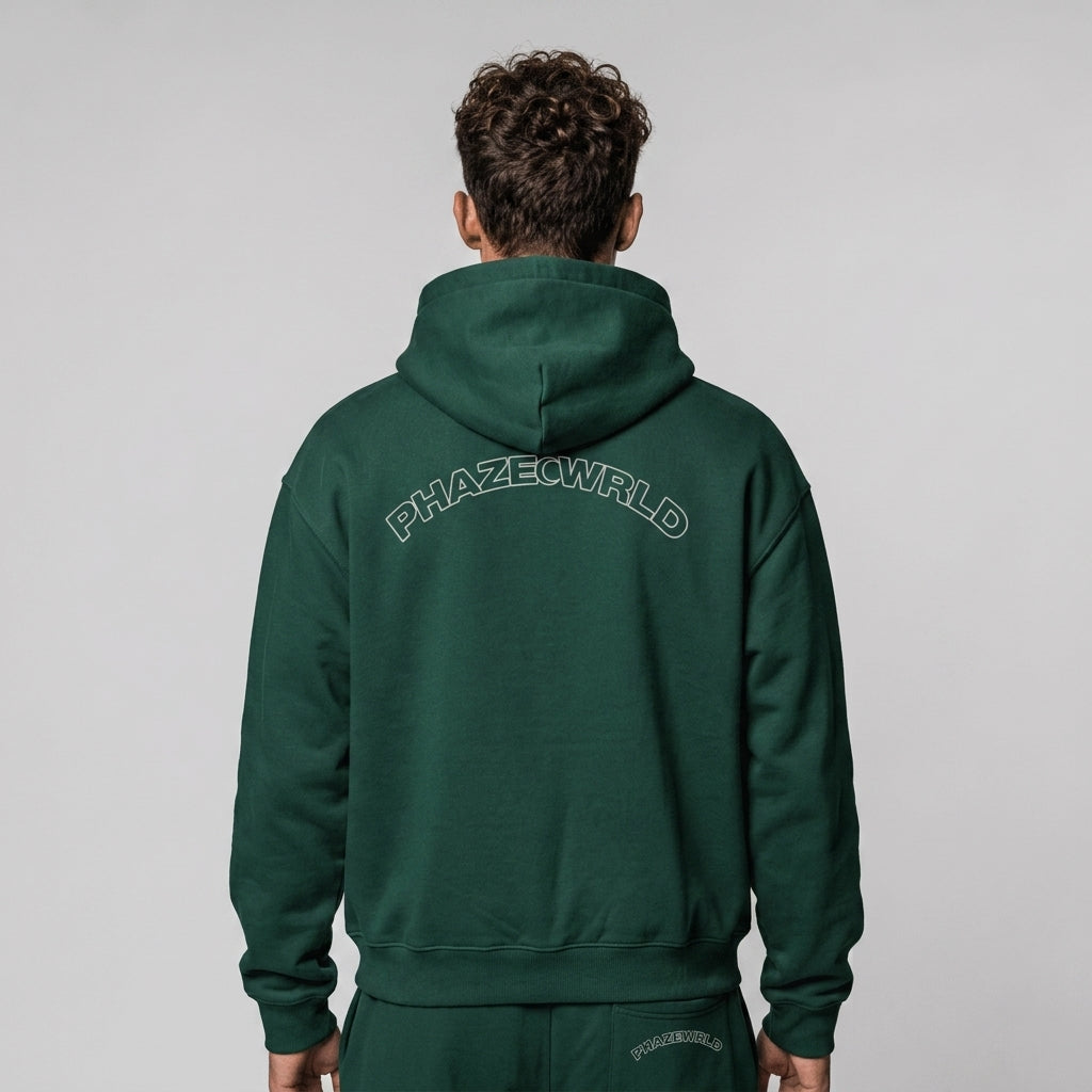 Back view of a premium forest green oversized streetwear hoodie featuring an arched white outline PHAZEWRLD graphic across the shoulders.