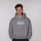 Model wearing the grey Into The Phaze Boxy Hoodie, front view highlighting the kangaroo pocket and chest graphic.