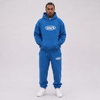 Model wearing the Lapis Blue Stellar Boxy Hoodie and sweatpants, front view showing the kangaroo pocket and chest logo.