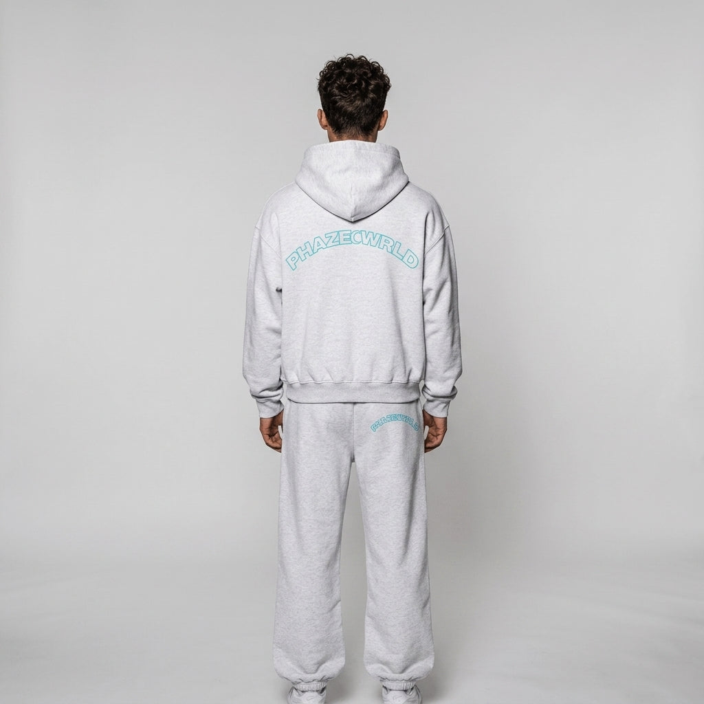 Back view of an oversized light heather grey streetwear hoodie featuring a bright cyan arched outline graphic spelling PHAZEWRLD across the shoulders.