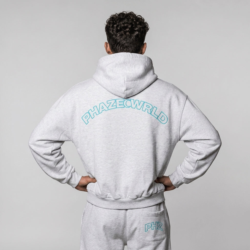 Back view of a premium light heather grey oversized streetwear hoodie featuring a cyan blue arched PHAZEWRLD outline graphic across the shoulders.