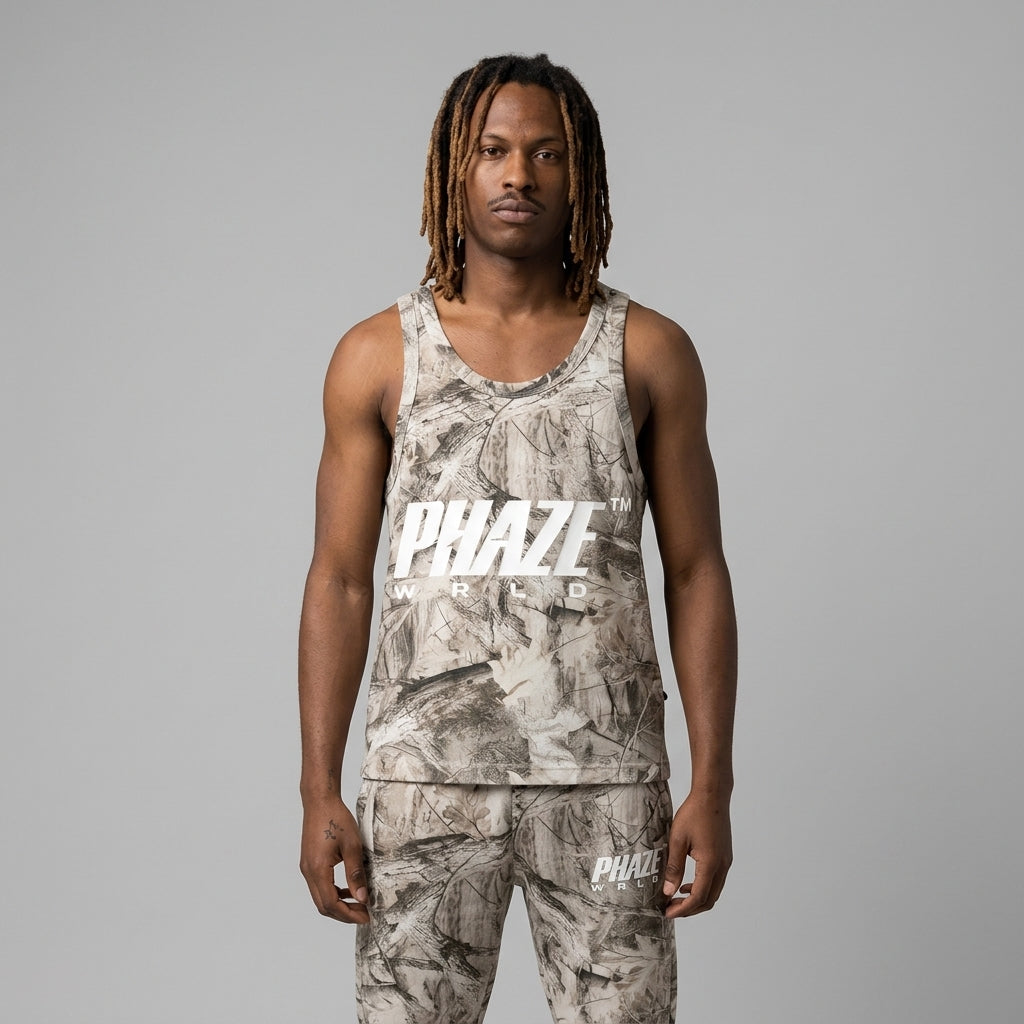 A streetwear sleeveless tank top featuring a beige and taupe real-tree camouflage pattern and a bold white PHAZE WRLD chest logo graphic.