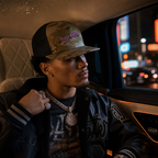 Model wearing the Multicam Arid/Brown Trucker Cap, side view showing the pink 'PHAZE WRLD' front graphic and brown mesh.
