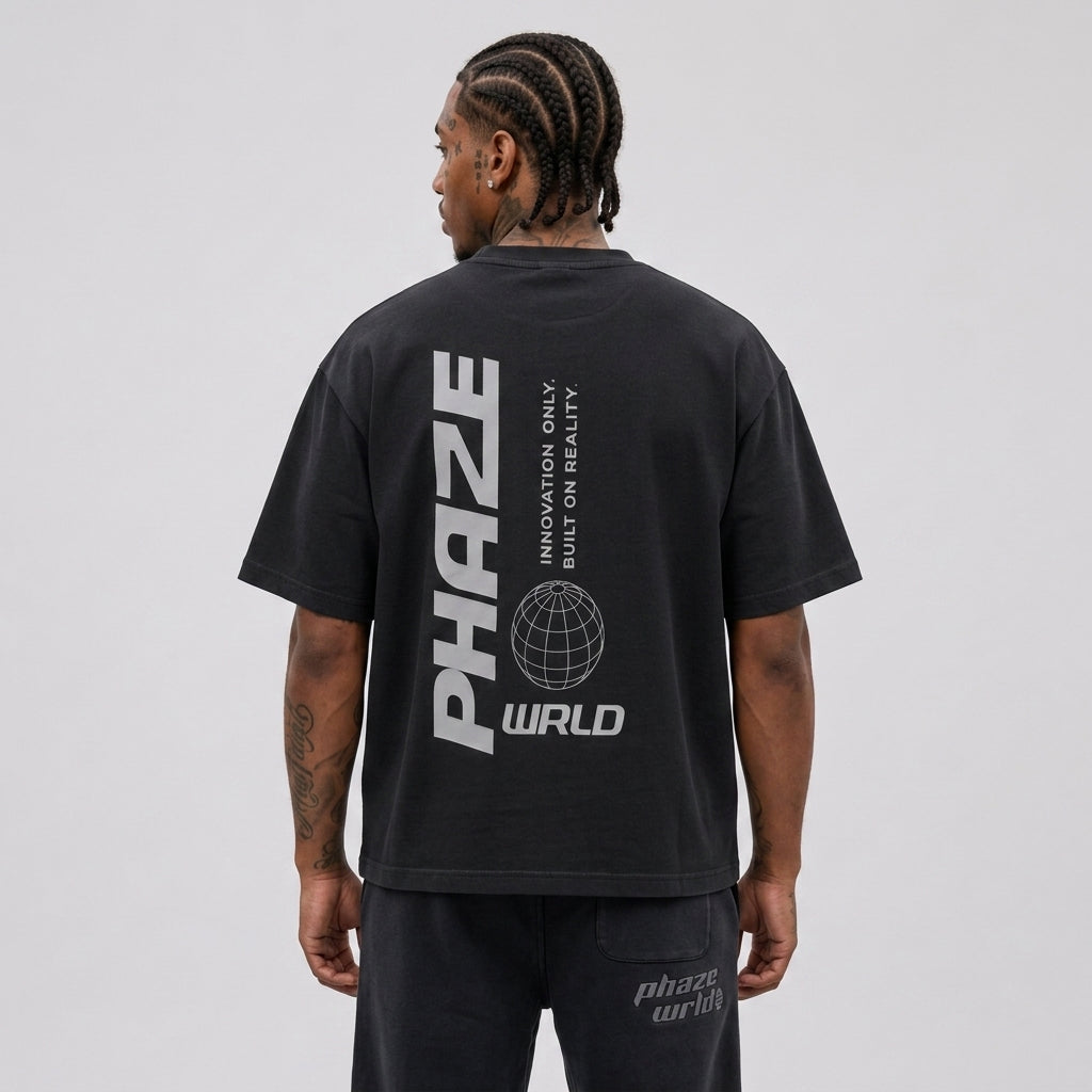 Back view of a premium oversized washed black streetwear t-shirt with a minimalist light grey vertical PHAZE WRLD globe graphic.