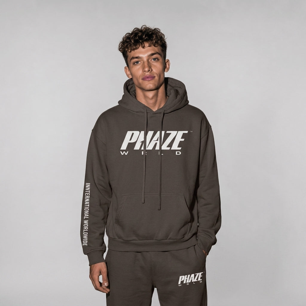 A professional lookbook photo of a premium oversized espresso brown heavyweight streetwear hoodie with white graphics and vertical sleeve text.