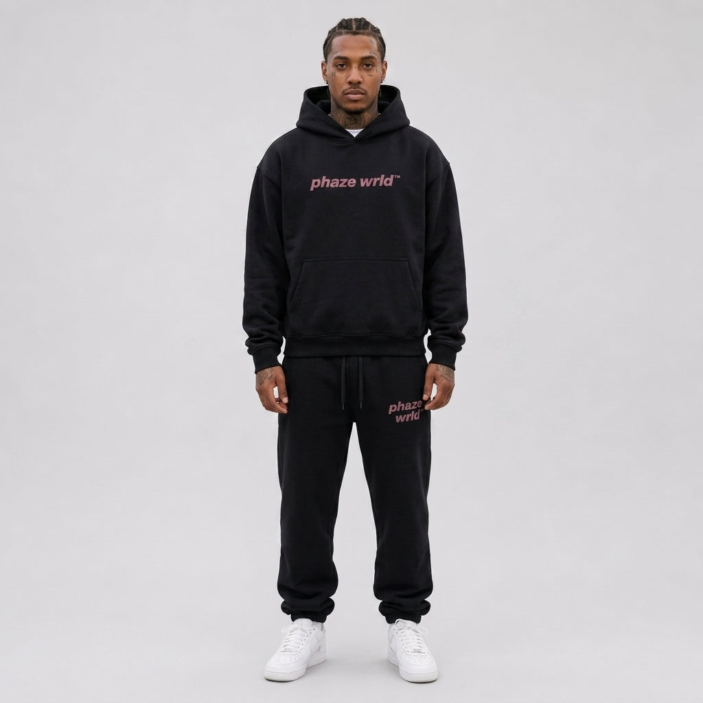 A studio lookbook photo of a premium heavyweight black oversized streetwear hoodie featuring a dusty pink phaze wrld chest logo.
