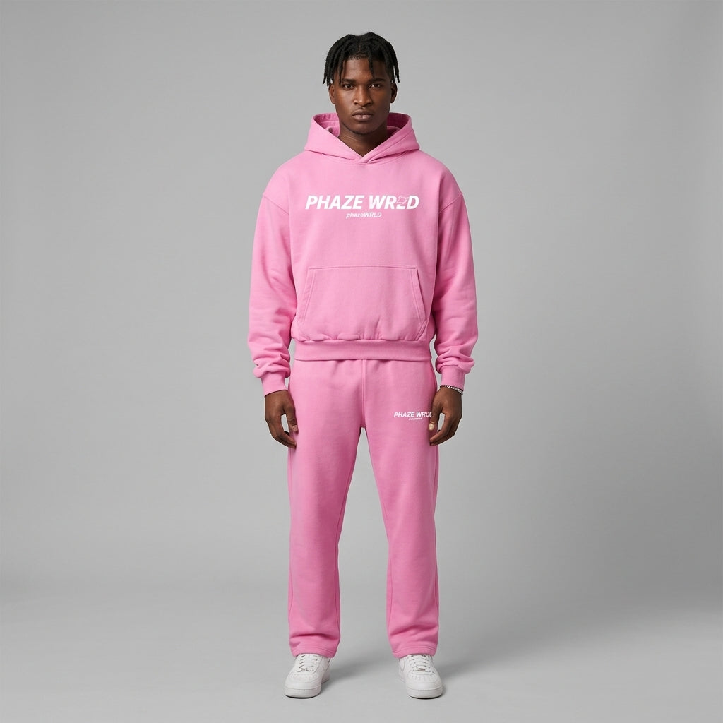 A studio lookbook photo of a premium bubblegum pink cropped streetwear hoodie featuring dropped shoulders and a white center-chest graphic.