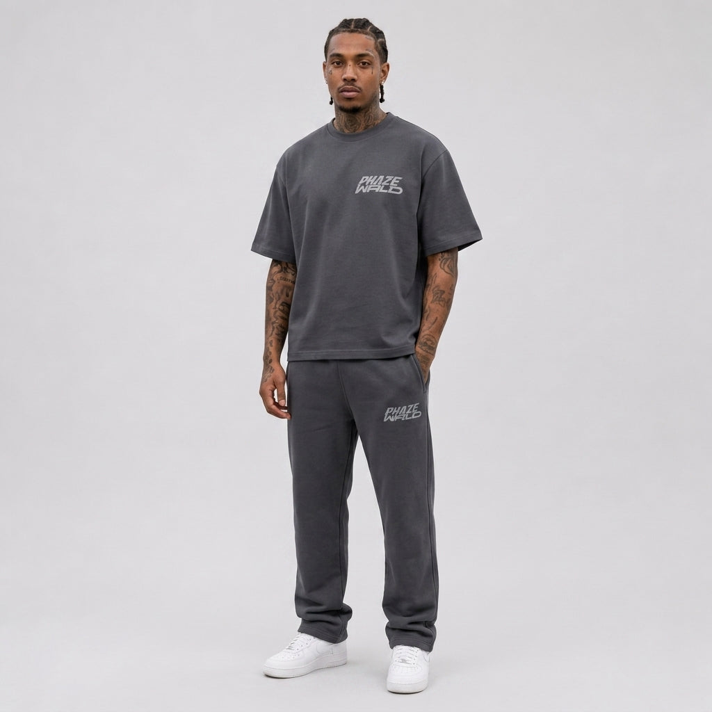 A studio product shot of a premium charcoal grey oversized streetwear t-shirt with a minimalist light grey Phaze Wrld chest graphic.