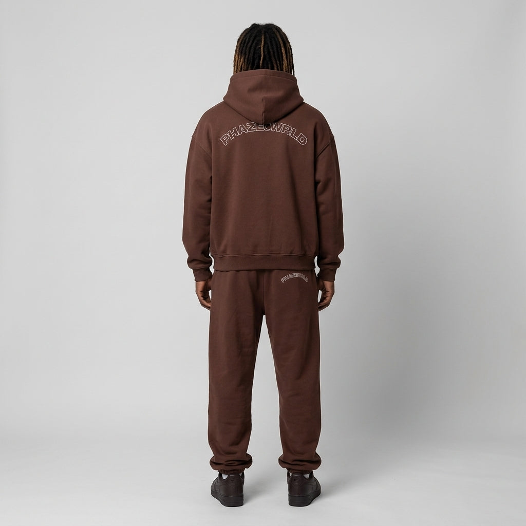 Back view of a premium heavyweight oversized chocolate brown streetwear hoodie featuring a white arched outline PHAZEWRLD graphic across the shoulders.
