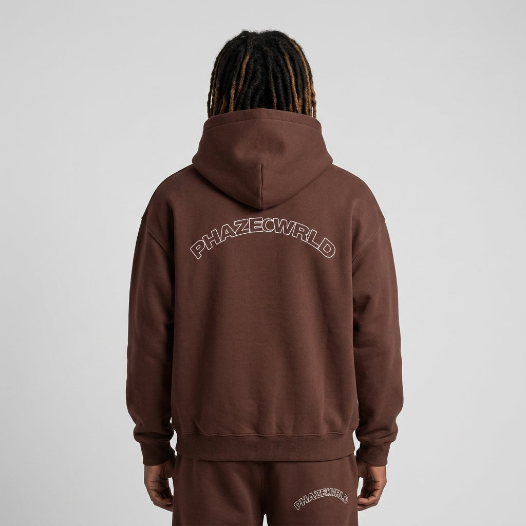 Back view of a premium heavyweight chocolate brown oversized streetwear hoodie featuring a clean arched white outline PHAZEWRLD logo across the shoulders.
