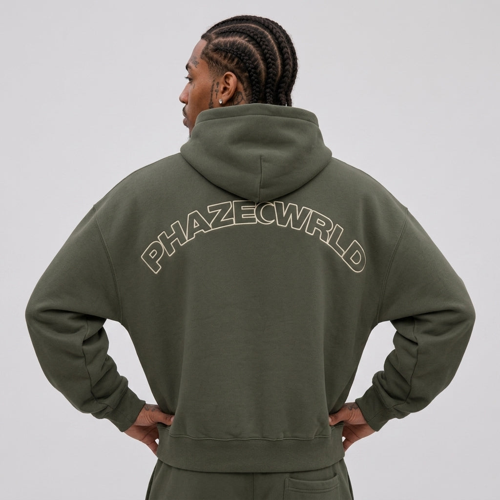 Back view of a premium oversized olive green cropped streetwear hoodie featuring a cream arched outline PHAZECWRLD graphic.