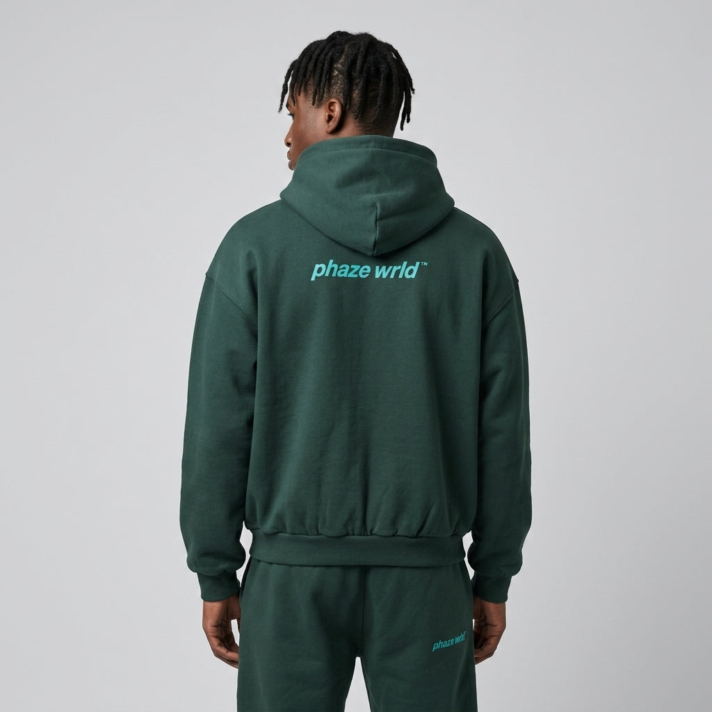 Back view of a premium deep pine green oversized streetwear hoodie with a cyan "phaze wrld" brand graphic printed across the upper back.