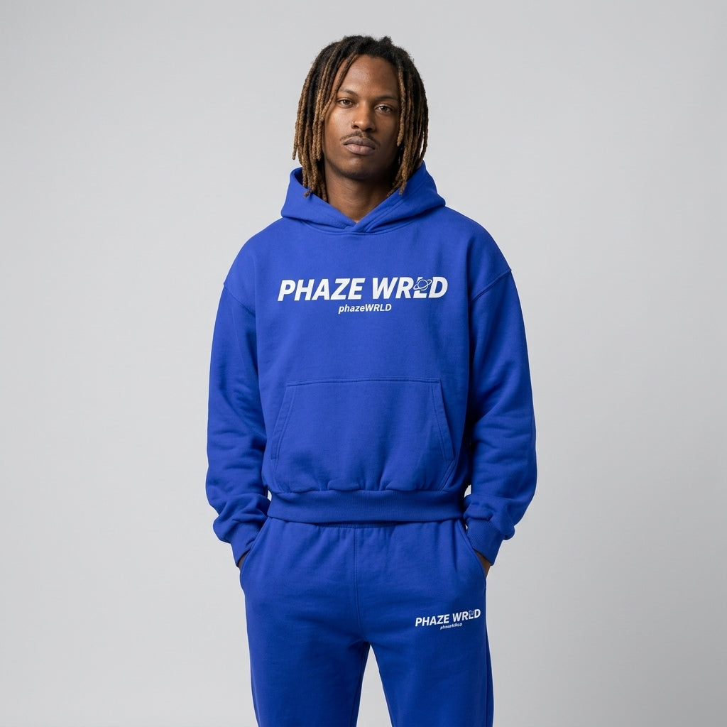 Premium royal blue oversized streetwear hoodie featuring a bold white planet graphic logo on the center chest, boxy drop-shoulder fit.