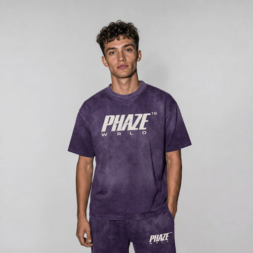 A premium washed purple oversized streetwear graphic t-shirt with a vintage fade, thick crewneck collar, and central off-white PHAZE WRLD chest logo.