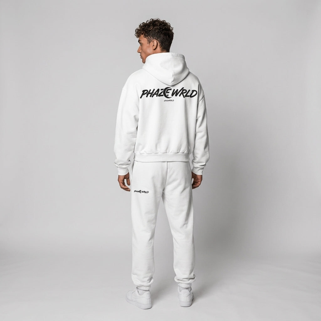 Rear view of a model in a premium white oversized streetwear hoodie featuring a bold black "PHAZE WRLD" crescent moon graphic on the back.
