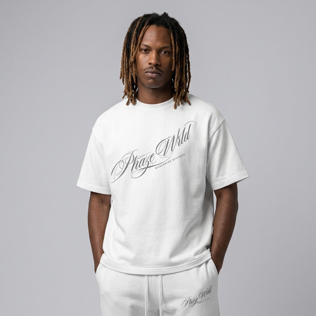 A premium white relaxed-fit streetwear t-shirt featuring a diagonal grey calligraphic script graphic across the chest.