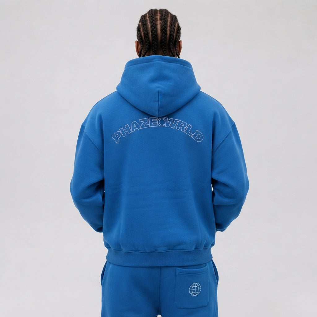 Back view of a premium royal blue oversized streetwear hoodie featuring a white arched outline PHAZECWRLD graphic on heavyweight cotton.