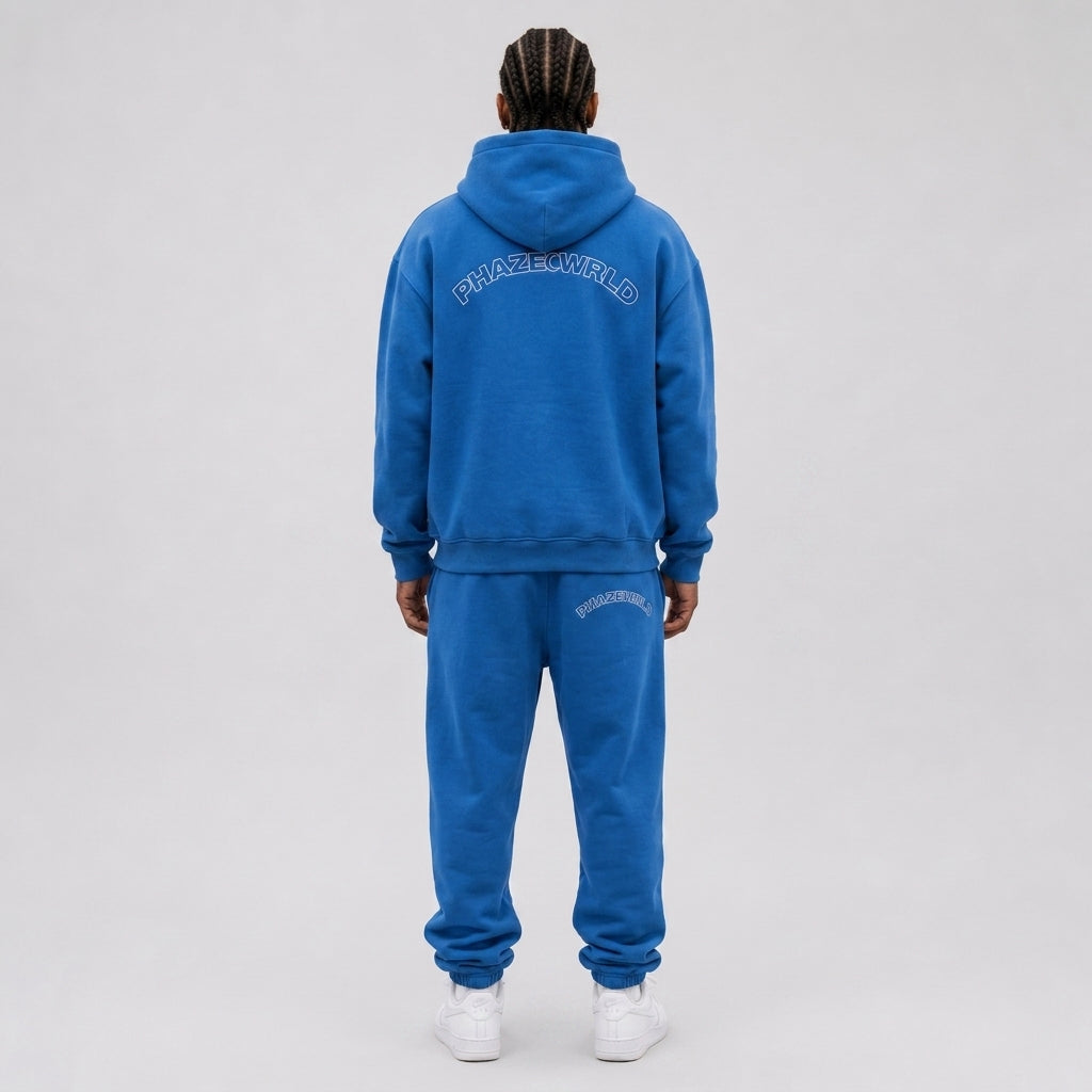 Back view of a premium royal blue oversized streetwear hoodie with an arched white outline PHAZEWRLD graphic across the upper back.