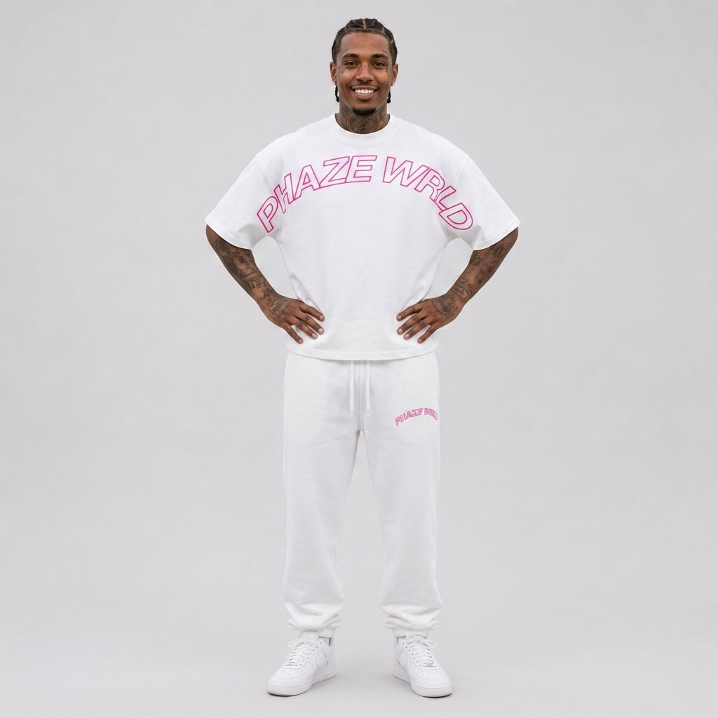 A streetwear model wearing a premium white oversized cropped t-shirt featuring a neon pink arched outline graphic reading PHAZE WRLD across the chest.