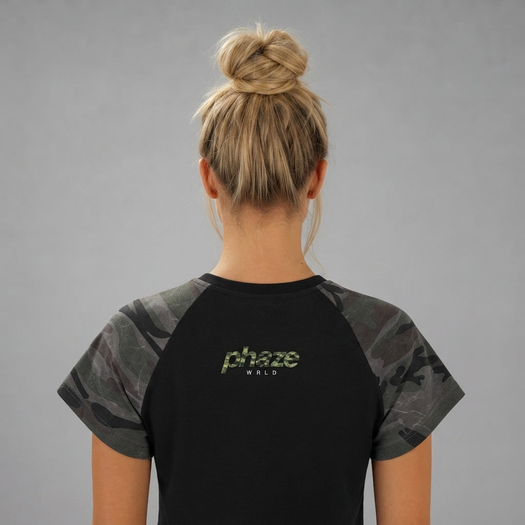 A studio product photo of a black cropped raglan baby tee with dark camouflage print sleeves and a central "phaze WRLD" chest graphic.