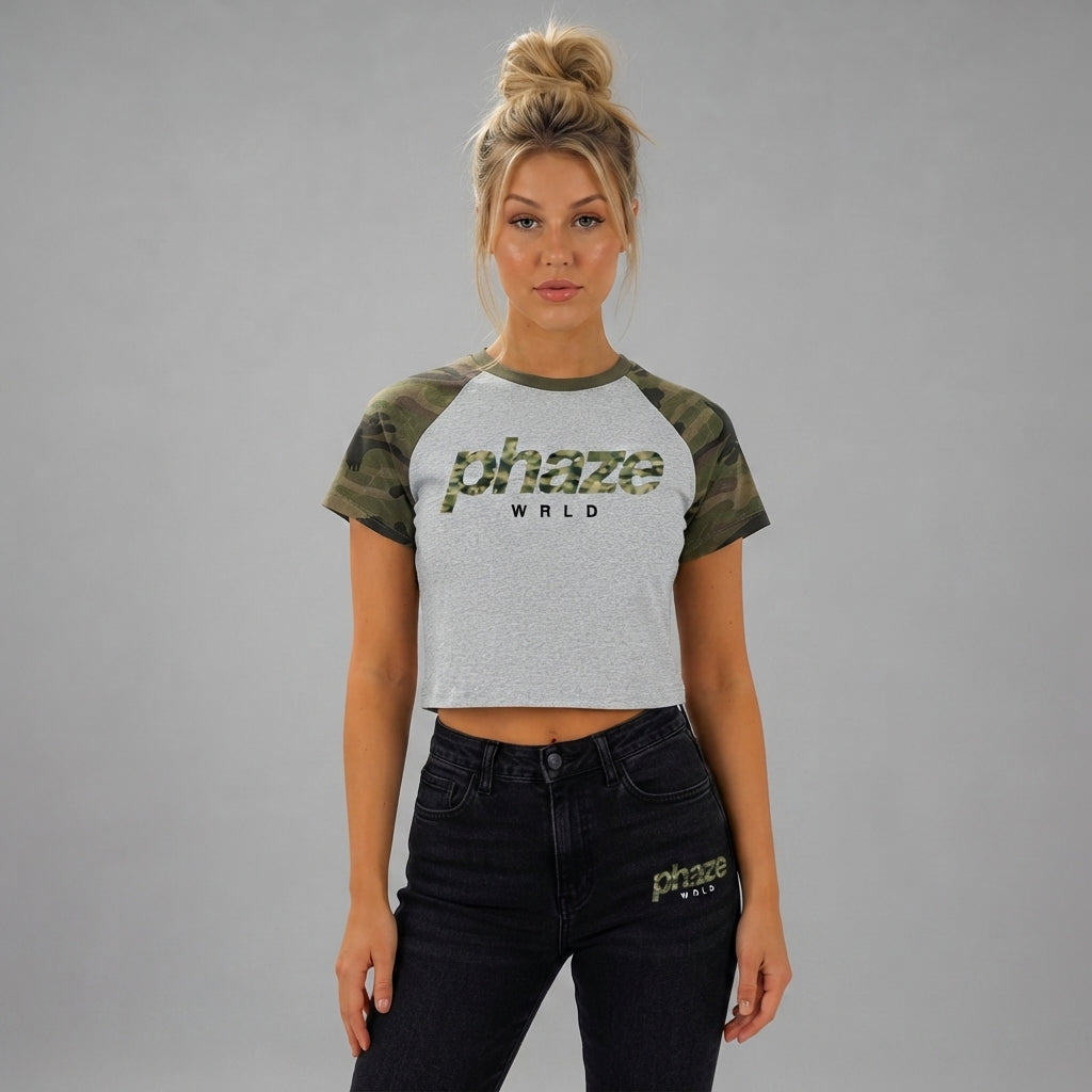 A flat-lay product photo of a women's cropped heather grey raglan t-shirt with green camouflage sleeves and a phaze WRLD graphic.